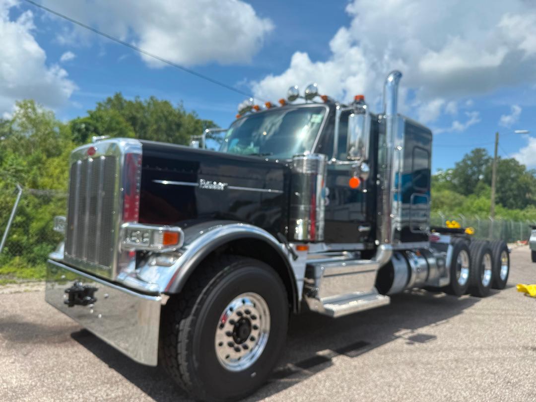 Peterbilt 589 heavy haul truck in black and chrome, front grille, dual exhaust stacks, chrome bumper, and triple rear axle configuration.