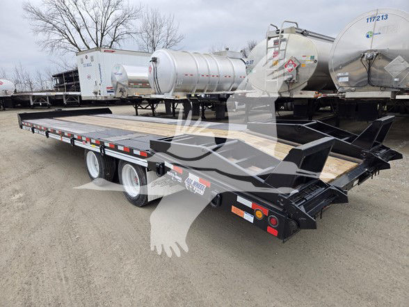 Flatbed trailer with dual rear axles and long wooden deck, behind are cylindrical tanks and equipment. Visible text on stickers along side: 'M.O.??' and reflective strips.