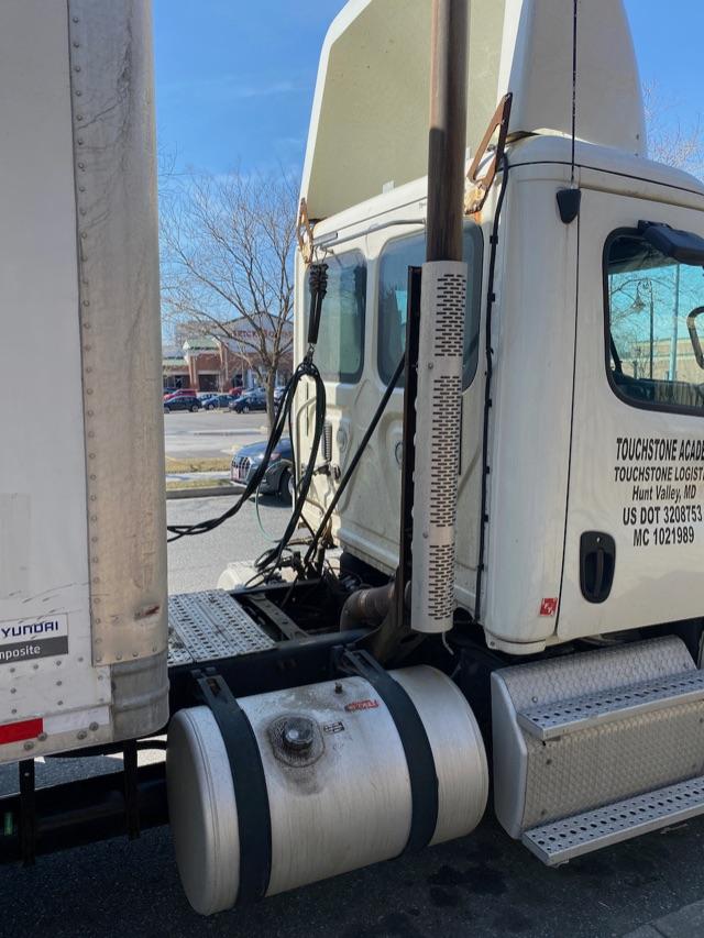 Truck cab and chassis side view showing fuel tanks, exhaust stack, and steps with Diamond plate. Text on door includes Touchstone Logistics and US DOT numbers.