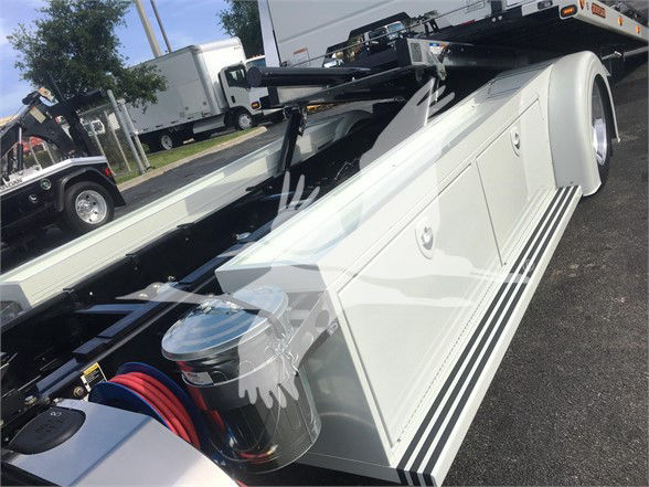 Peterbilt 337 tow truck chassis with white storage compartments and hydraulic components visible.