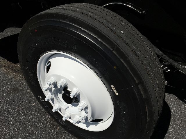 Wheel and tire close-up on a white steel rim with lug nuts, part of a Kalmar Ottawa YT30 yard truck.