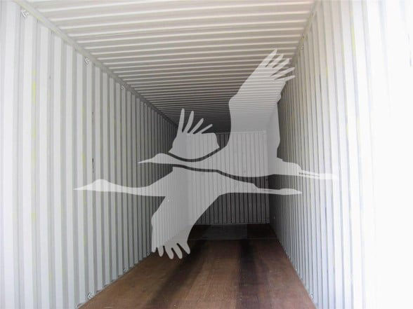 Inside a 40' high cube shipping container showing wooden floor, corrugated steel walls, and roof beams.