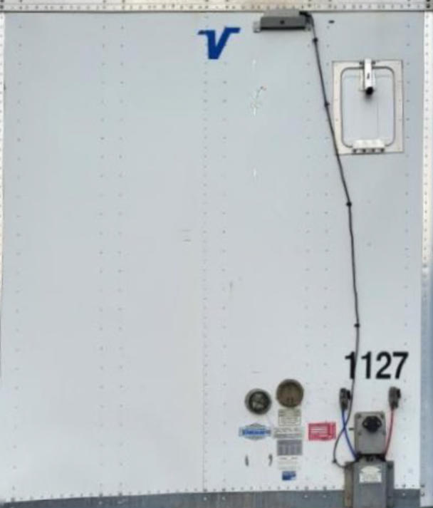 Rear view of a white Vanguard VXP trailer showing the number 1127, utility access door, and a vertical black cable along the door.