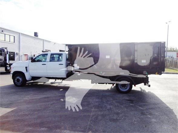 Alt text could not extract as image shows a white service truck with a large black and gray refuse body. No readable text labels visible on components or stickers.