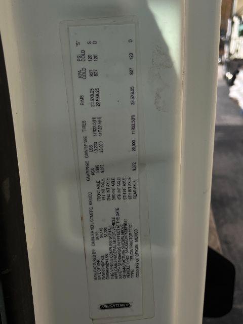 Label inside doorjamb with vehicle specs for Freightliner, including weights, capacities, and tire information.