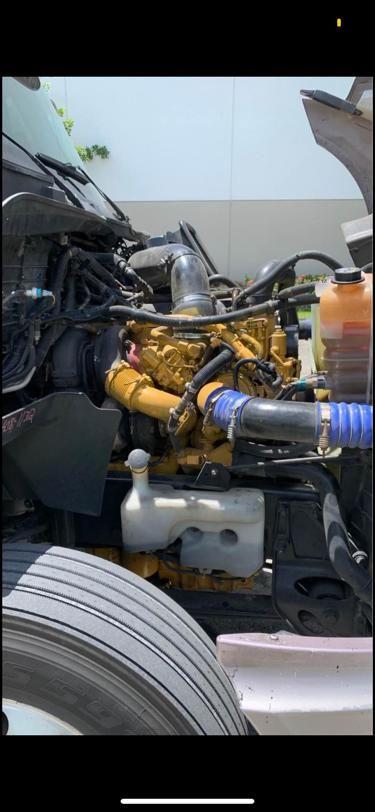 Engine bay of a 2009 International Prostar showing yellow diesel engine with hoses, coolant reservoir, and air intake hoses.