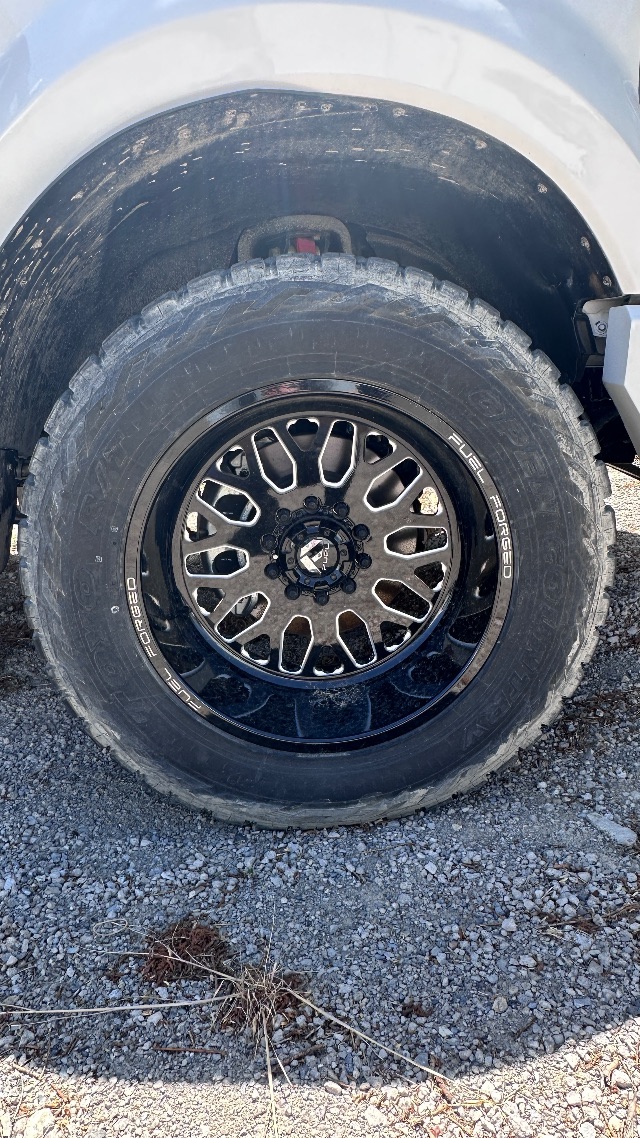 Ford F-550 Lariat wheel and tire showing rugged all-terrain tire and black multi-spoke rim, wheel well with mud and dirt.