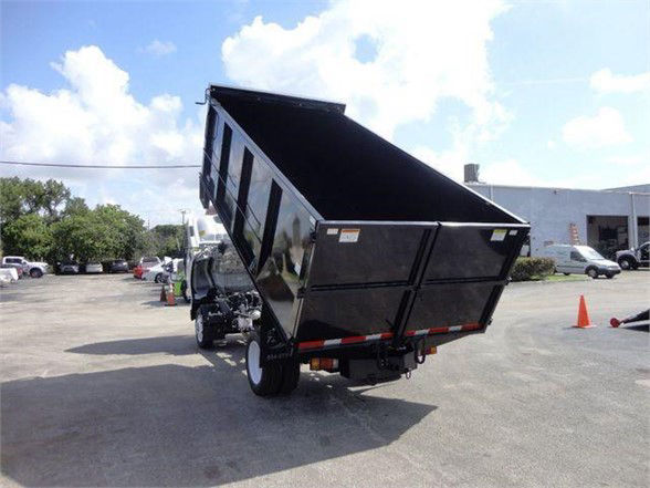 Isuzu NPR HD dump truck in raised dump position showing cargo bed and rear wheels.