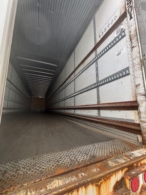 Trailer interior showing long dry van cargo space with aluminum side rails and stamped metal floor, exterior access at door with Stoughton markings.