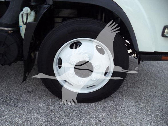 Isuzu NRR box truck front wheel and fender with white steel wheel and tire, partial cab side, water reservoir visible.