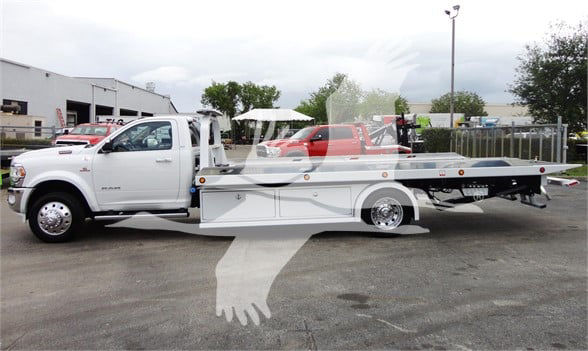 Ram 5500 HD SLT tow truck in white with flatbed, side view showing cab and long bed.