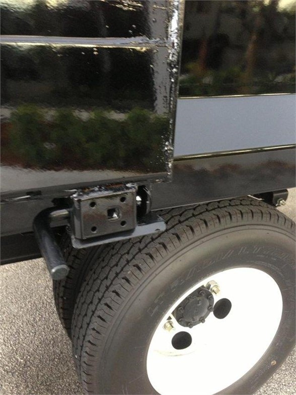 Truck bed side showing rear wheel and mounting bracket for dump body with black glossy paint and white steel wheel.