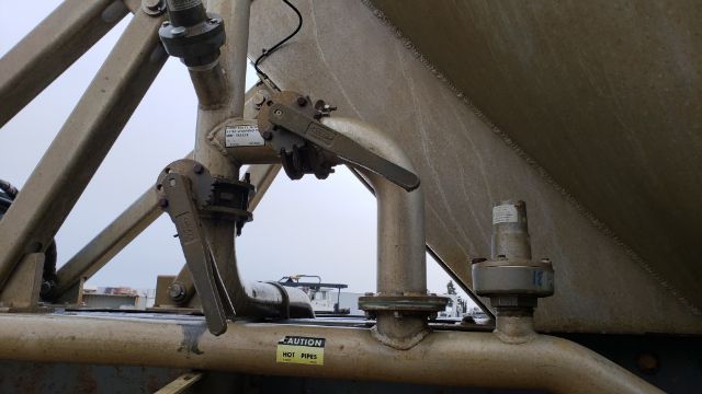 Trailer valve and piping with manual levers and a caution label visible on a Polar Pneumatic 38 M3 tanker trailer assembly.