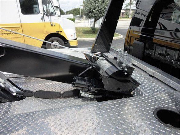 Tow hitch mechanism on a Ram 4500HD tow truck, with metal diamond plate deck and hydraulic components visible.