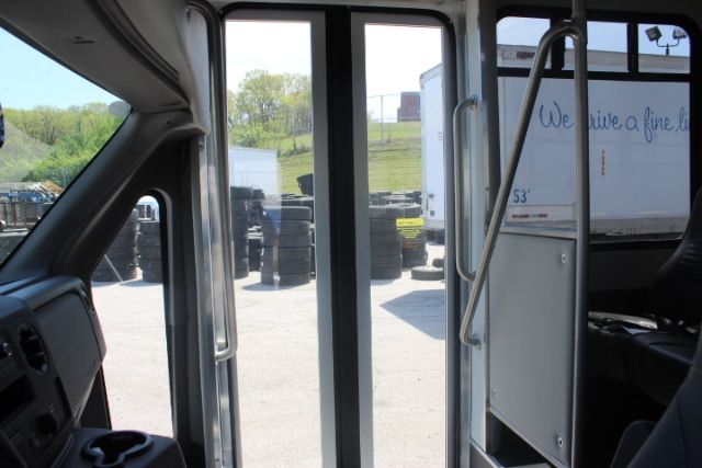 Ford E-450 shuttle bus interior showing entry doors and driver area with exterior tires visible outside.