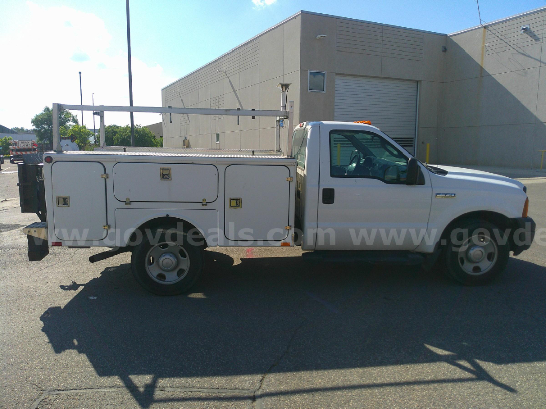 Service/utility truck side view showing multiple storage compartments and utility ladder rack on white Ford F-350 with orange beacon light.