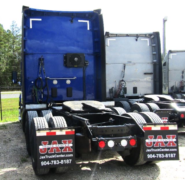 Kenworth T680 tractor rear view showing blue cab and Chassis with JAX Truck Center mudflaps and contact number.