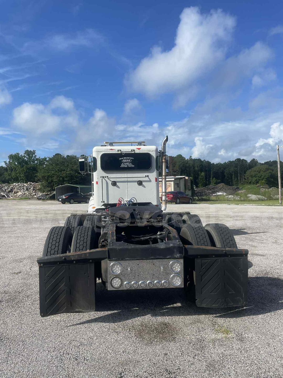 Peterbilt 386 bare chassis cab with dual rear axles and utility toolbox, rear view showing dual fifth wheels and exhaust stack.
