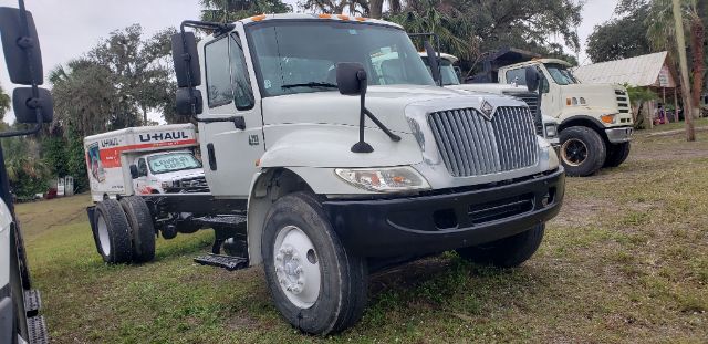 2005 International cab and chassis truck shown in a used lot with U-Haul branding on the rear bed and another truck in the background.