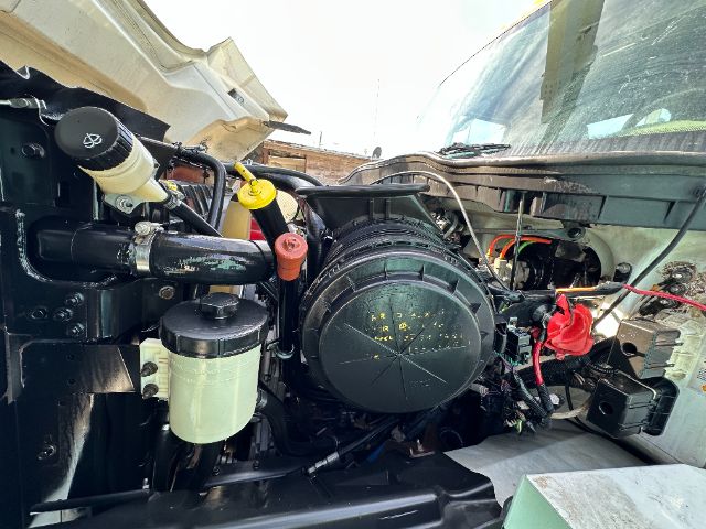 Engine bay of 2013 International 7500 truck showing air intake, coolant reservoir, wiring, and various hoses.