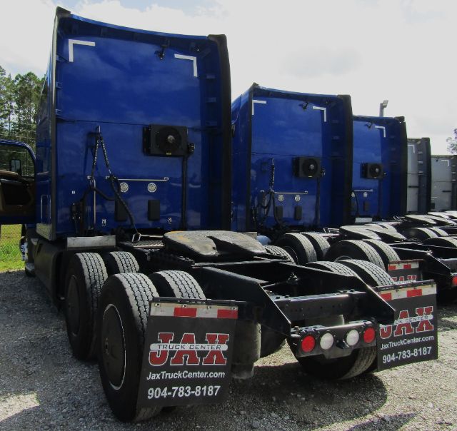 Blue semi tractor chassis from rear showing multiple trucks with cab sections in a row. Visible text includes JAX Truck Center URLs and phone numbers on mud flaps: 904-783-8187.