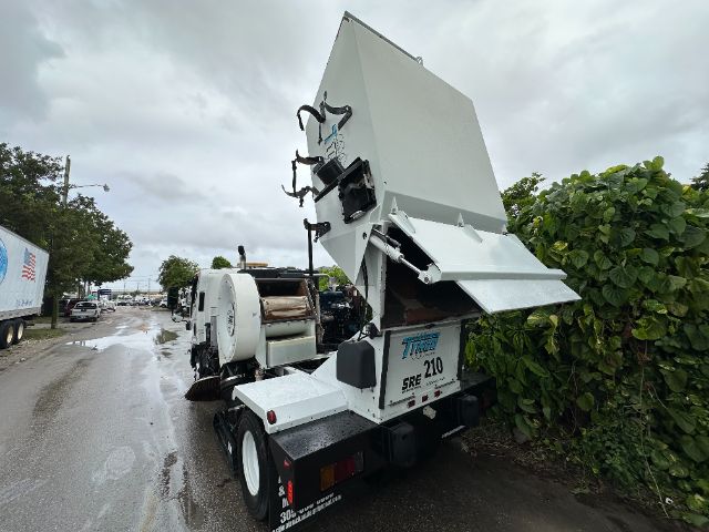 Isuzu NPR-HD sweeper truck rear with hopper raised showing cleaning equipment and rear chute