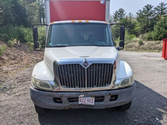 Front view of a white 2005 International 4300 box truck with large chrome grille, yellow clearance lights, and a red box rear. California license plate RZ-901.
