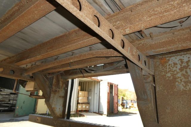  Trailer frame showing rusted steel beams and underside of a Fruehauf H2 trailer with support members; background shows a storage yard.
