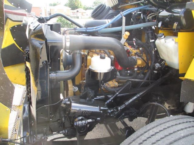 Kenworth T300 engine bay showing large intake hose, coolant reservoir, and hydraulic components.