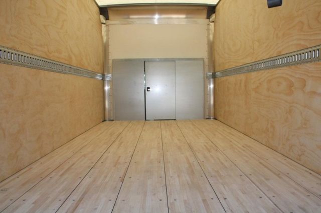 Box truck interior showing plywood walls and cargo space with metal partition at the front and a small door in the wall.