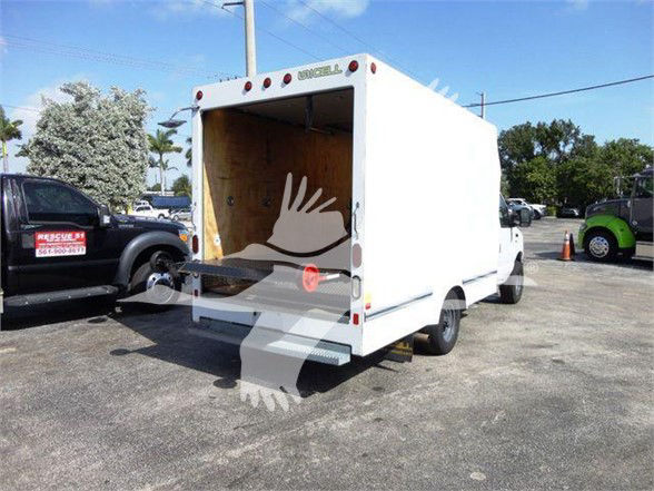 2015 Ford E350 SD box truck with rear cargo area open; white exterior; taillights visible; street with other vehicles in background.