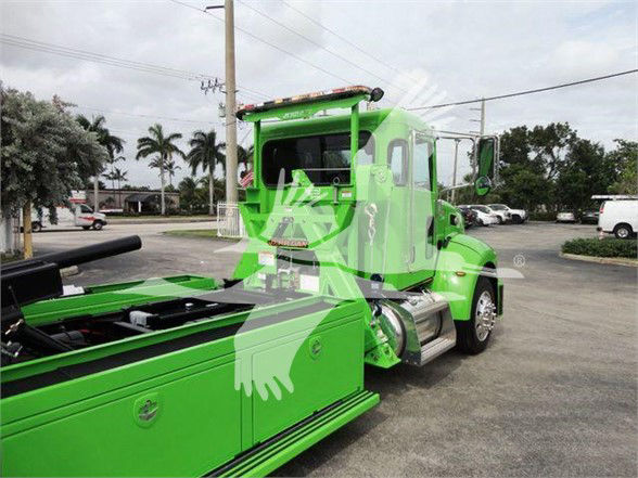 Green 2022 Peterbilt 337 tow truck side view with flatbed extendable bed and chrome fuel tanks
