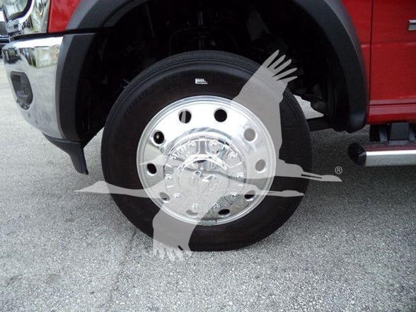 Wheel and chrome hubcap on front wheel of a red Ram truck; visible near tire with partial fender; no legible branding aside from wheel hubcap reflections.