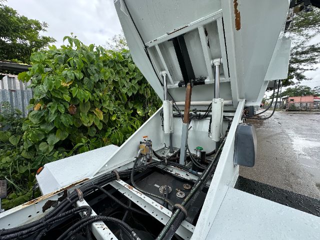 Isuzu NPR-HD sweeper truck with rear equipment exposed showing hydraulic controls and battery compartment.