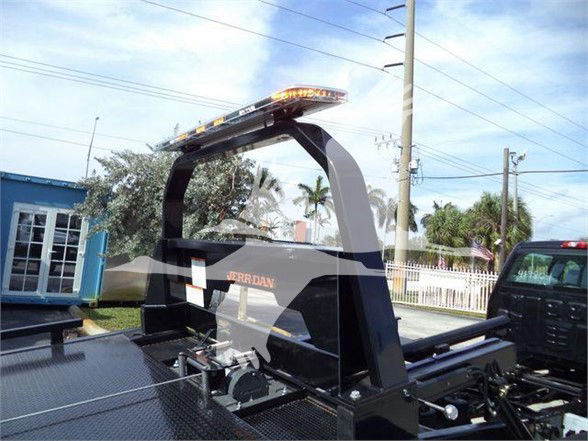 Truck bed with a black rollover protection structure and a light bar, International CV tow truck; visible 'JERRDAN' label on the rack.