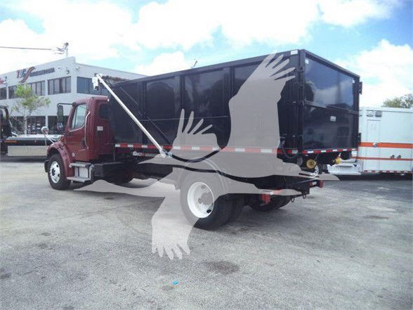 Truck in a yard showing a Freightliner Business Class M2 106 dump body with maroon cab and black dump bed.