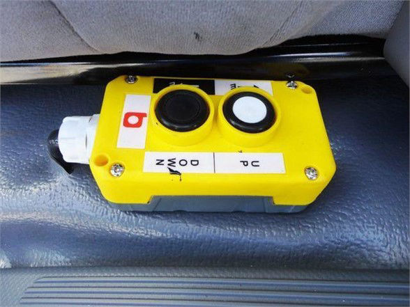 Yellow emergency stop device or control module with two circular ports labeled N and D and P C, mounted inside a vehicle cabin area.
