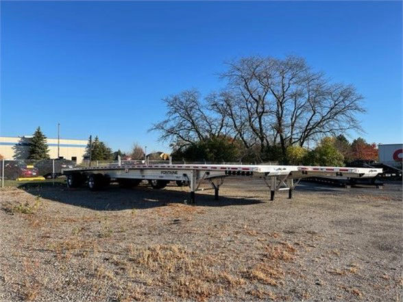 Fontaine Revolution trailer with aluminum flatbed showing side rails and landing gear, stocked on a gravel lot.