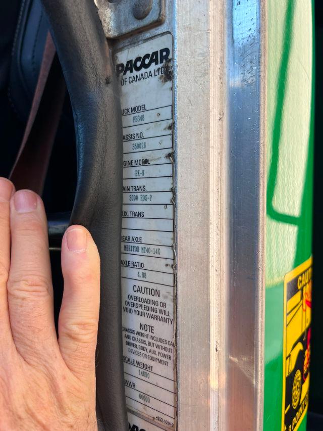 Trucker side panel with ID plate showing PACCAR of Canada Ltd, model PB348, gear numbers, axle data, and caution notes.