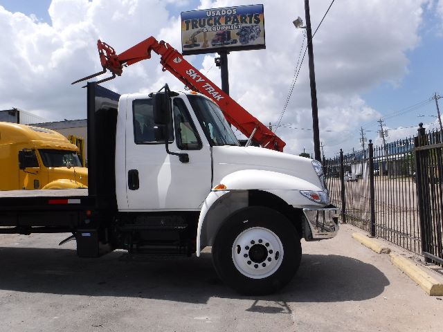 2018 International 4300 flatbed truck with a red crane arm mounted behind the cab, white body, side view.