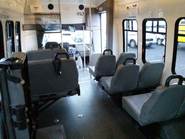 Interior of a used 2009 Ford E-450 bus showing seats and aisle, VIN 1FDFE45P39DA72529, 910 label, and windowed passenger area.