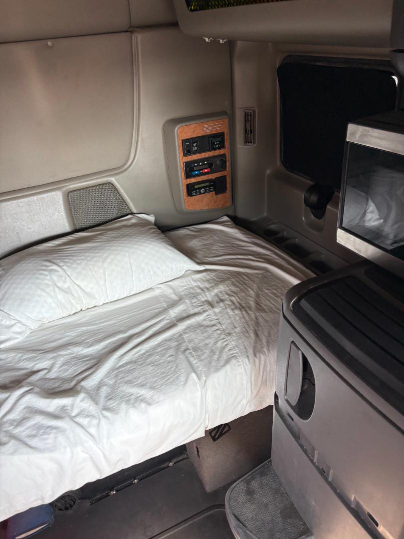 Interior of a 2016 International Prostar sleeper cab showing a bed with white bedding and control panels on the side wall.
