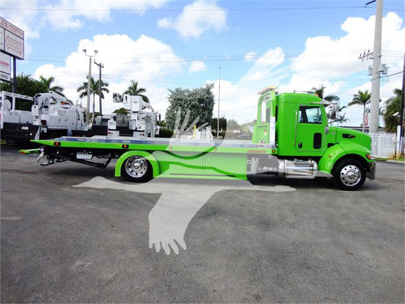 Peterbilt 337 tow truck with bright green and gray paint, flatbed, side view showing cab and long wheelbase.