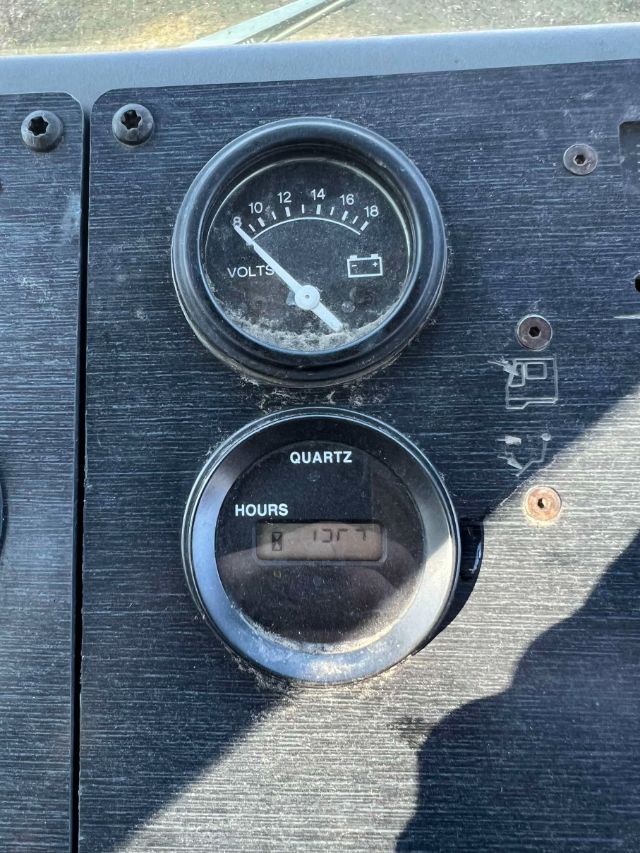 Dashboard gauges showing a volts gauge with a needle and a quartz hours meter on a black panel.