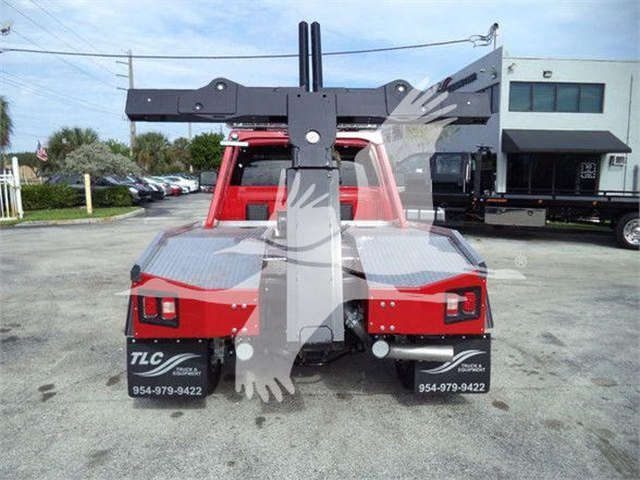 Rear view of a red Ram 4500 tow truck with a heavy-duty rear hitch/winch assembly and boom, license plate area branding, and TLC Global logo on mud flaps.