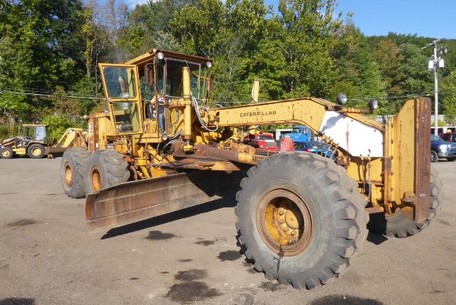 Front-left view of a yellow Caterpillar 16G motor grader with large tires and blade, labeled Caterpillar, in an outdoor lot.