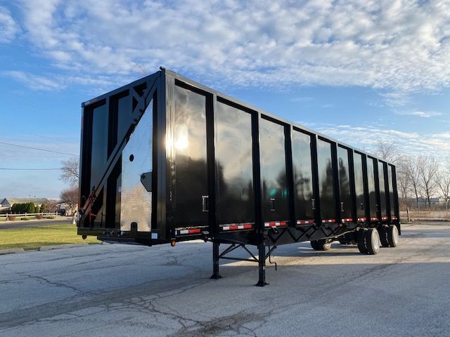 Transcraft 48 ft crush car carrier trailer in black, side view with landing legs deployed.