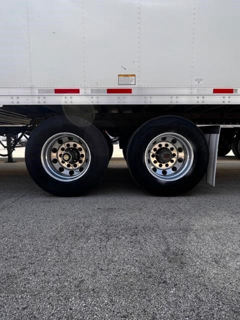 Dual rear axles of a white CIMC Cool Globe trailer showing wheels and undercarriage, with wheel rims and tire treads visible.