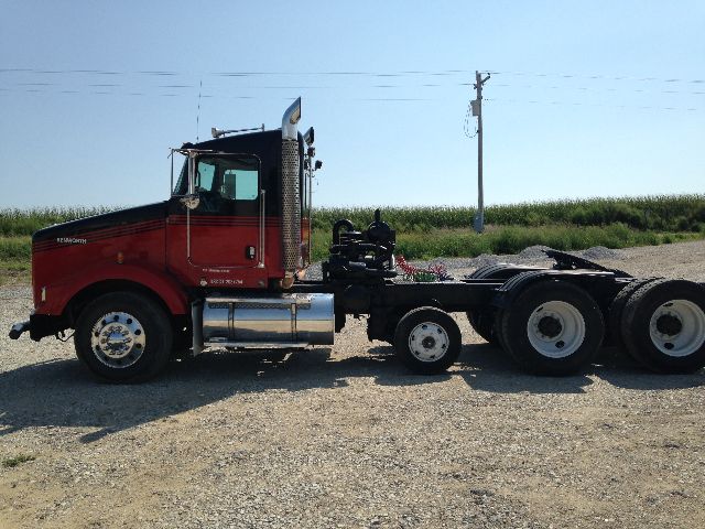 Kenworth T800 conventional daycab tractor in red with chrome fuel tanks and black chassis, side view showing cab, fuel tanks, and rear drivetrain.