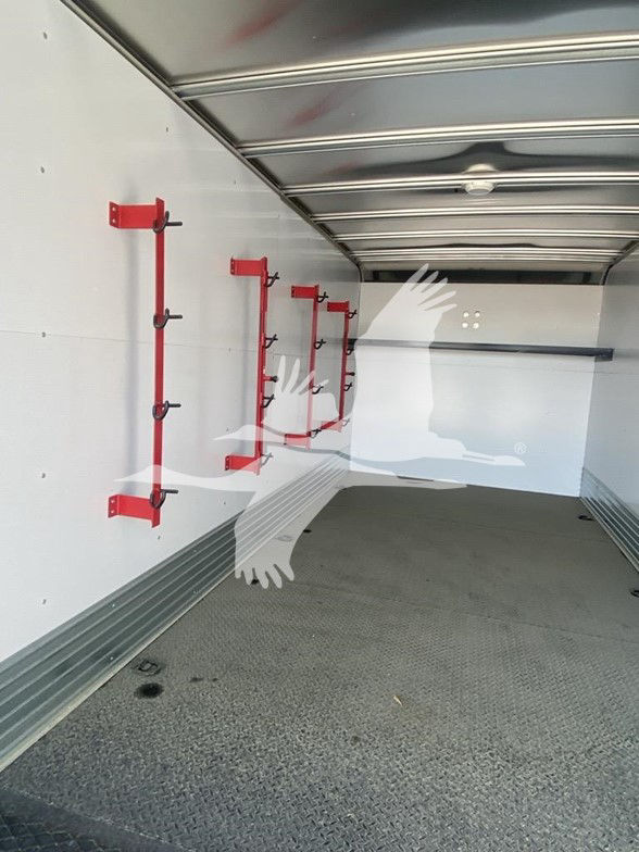 Interior of a new Isuzu NPR HD truck cargo area with white walls and red tool racks on the left side.
